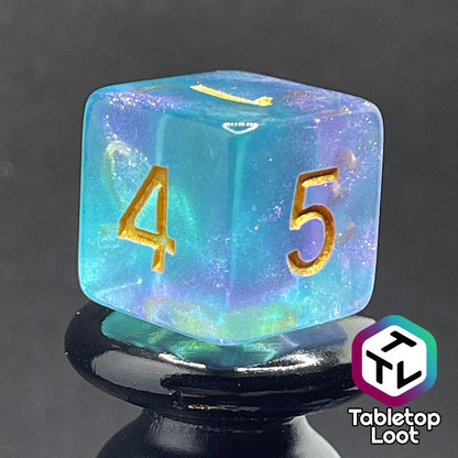 A close up of the D6 from the Shape Water 7 piece dice set from Tabletop Loot with swirls of glittery purple and blue resin and gold numbering.