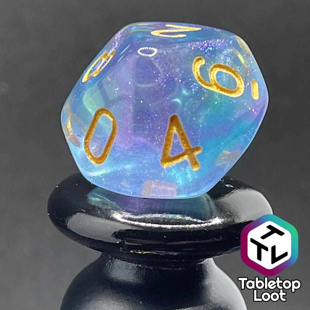 A close up of the D10 from the Shape Water 7 piece dice set from Tabletop Loot with swirls of glittery purple and blue resin and gold numbering.