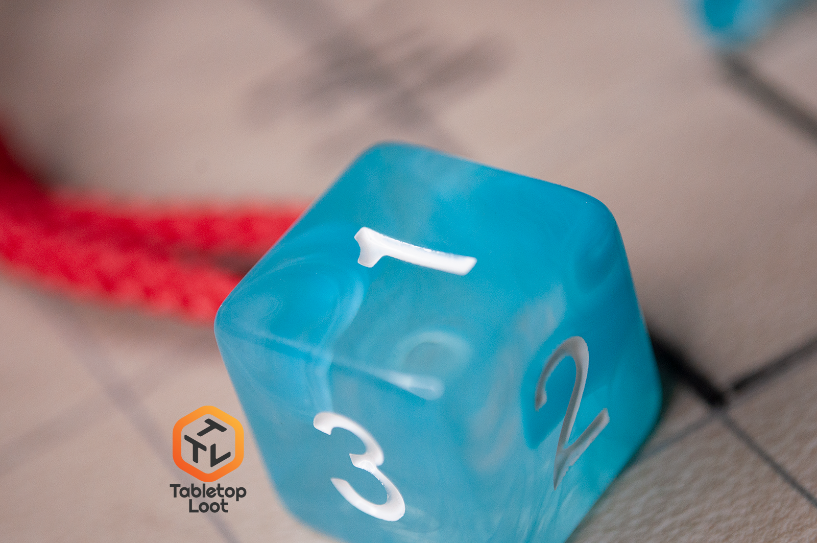 A close up of the D6 from the Sky Blue 7 piece dice set from Tabletop Loot with blue and white swirls in clear resin and white numbering.