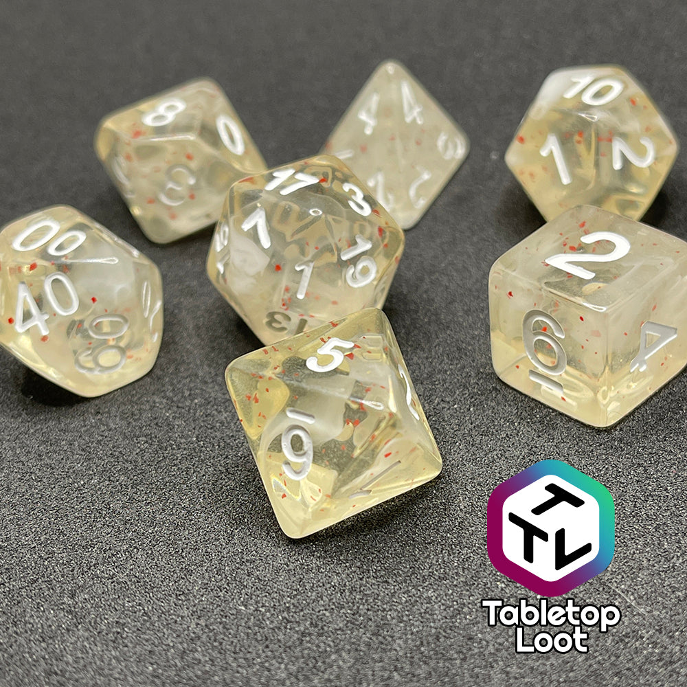 A close up of the Spore Cloud 7 piece dice set from Tabletop Loot with swirls of white and speckles of red suspended in clear resin and white numbering.
