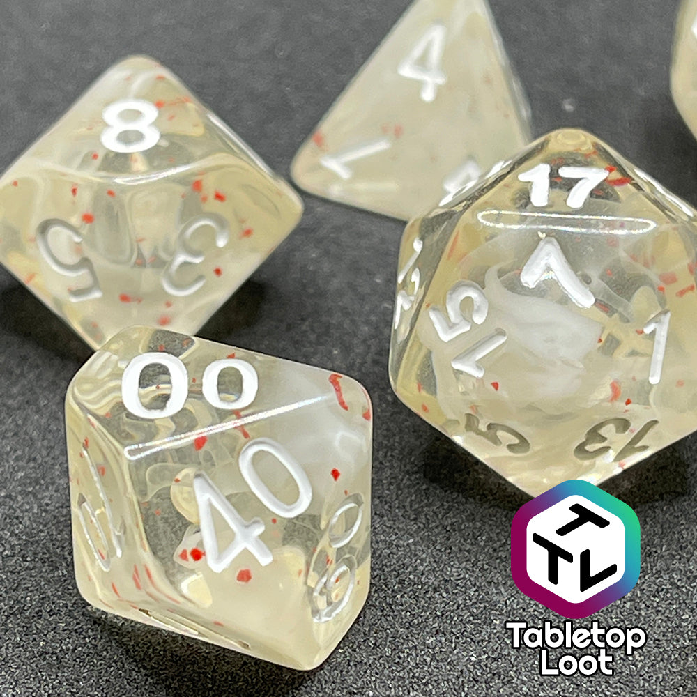 A close up of the percentile die and the D20 from the Spore Cloud 7 piece dice set from Tabletop Loot with swirls of white and speckles of red suspended in clear resin and white numbering.