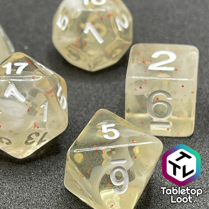 A close up of the D8, D6, and D20 from the Spore Cloud 7 piece dice set from Tabletop Loot with swirls of white and speckles of red suspended in clear resin and white numbering.