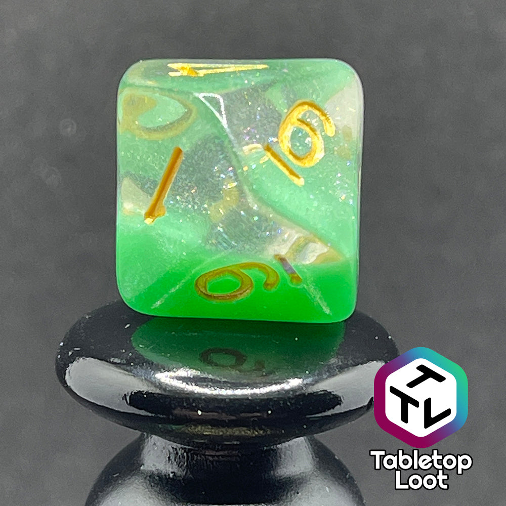 A close up of the D10 from the Spring Dew 7 piece dice set from Tabletop Loot with a layer of shimmery light green under shimmery clear resin and gold numbering.