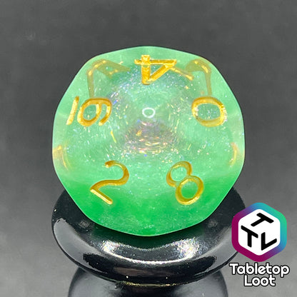 A close up of the D10 from the Spring Dew 7 piece dice set from Tabletop Loot with a layer of shimmery light green under shimmery clear resin and gold numbering.