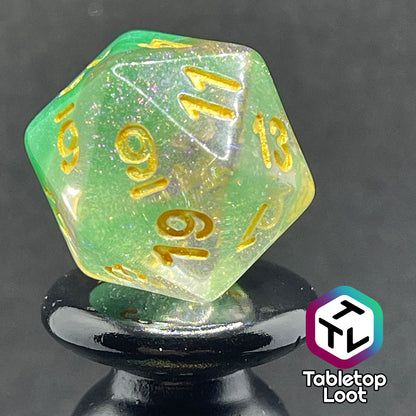 A close up of the D20 from the Spring Dew 7 piece dice set from Tabletop Loot with a layer of shimmery light green under shimmery clear resin and gold numbering.