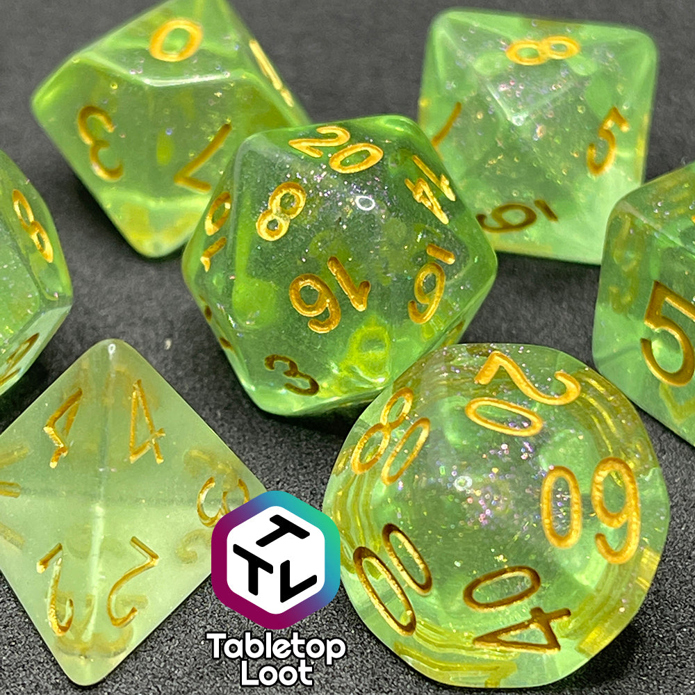 A close up of the Sprites 7 piece dice set from Tabletop Loot with light green translucent pigment packed with glitter and gold numbering.