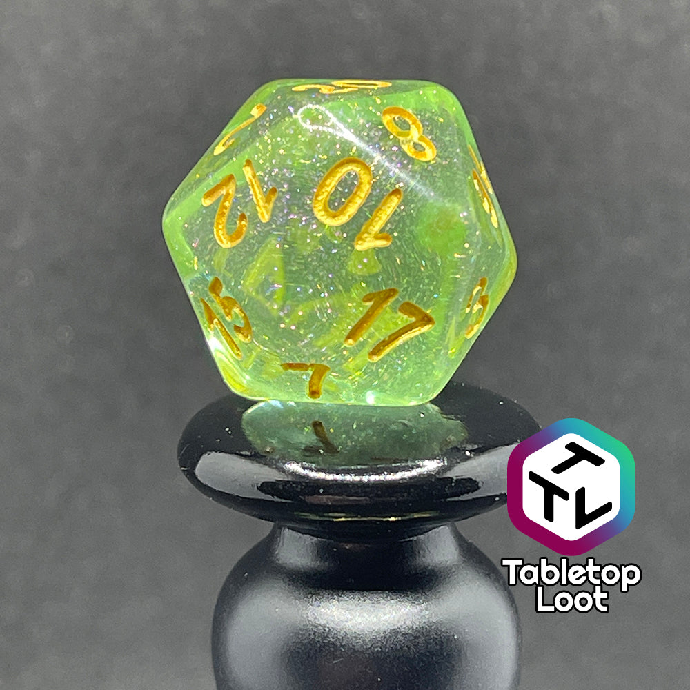 A close up of the D20 from the Sprites 7 piece dice set from Tabletop Loot with light green translucent pigment packed with glitter and gold numbering.