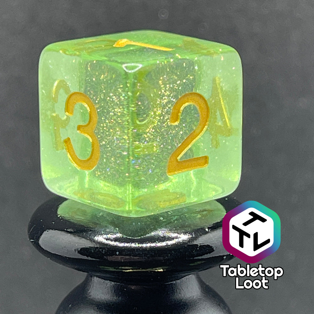 A close up of the D6 from the Sprites 7 piece dice set from Tabletop Loot with light green translucent pigment packed with glitter and gold numbering.