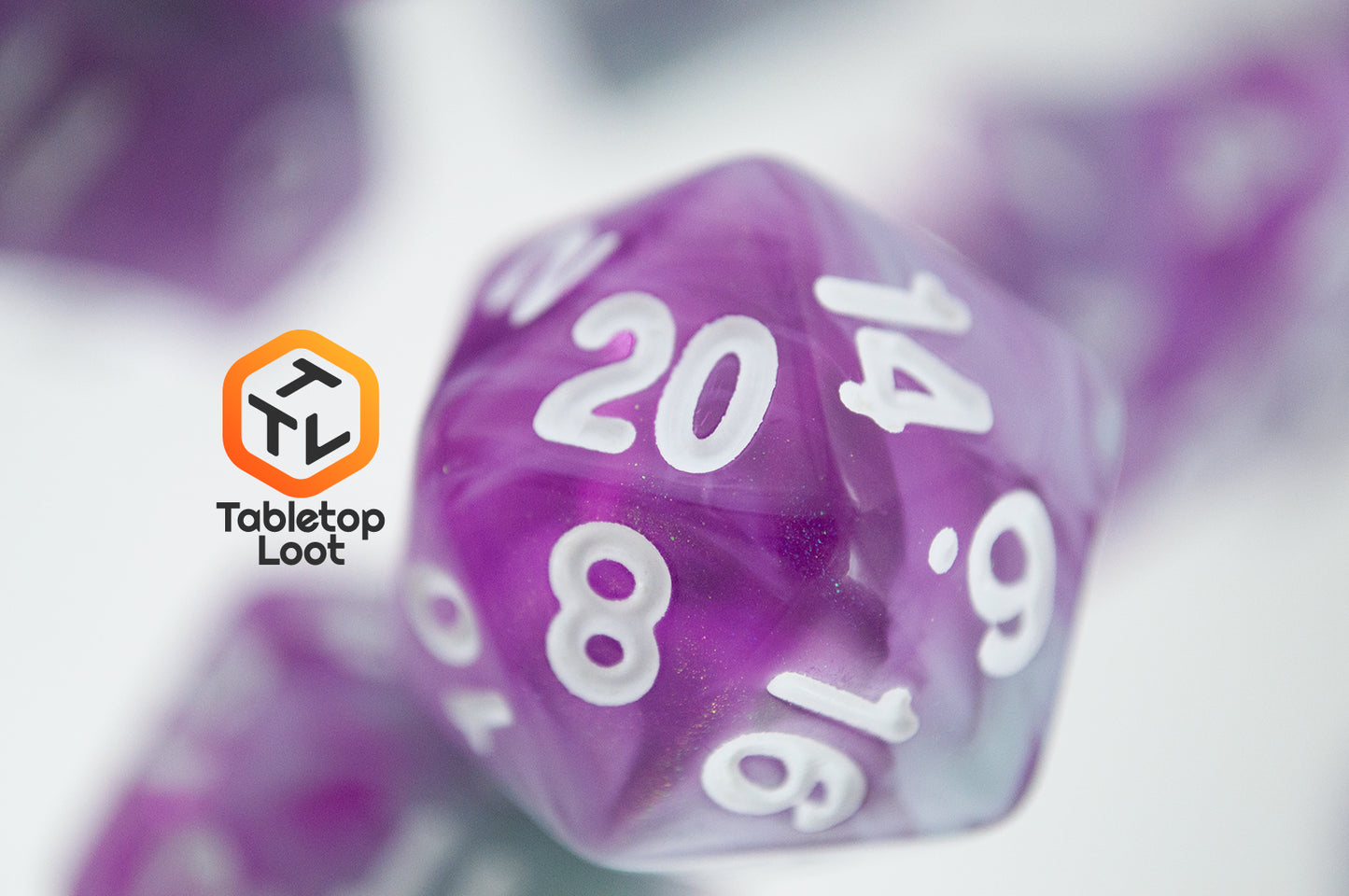 A close up of the D20 from the Stars Shine 7 piece dice set from Tabletop Loot with purple and grey shimmering swirls and white numbering.