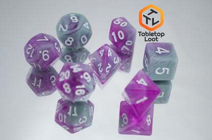 The Stars Shine 7 piece dice set from Tabletop Loot with purple and grey shimmering swirls and white numbering.