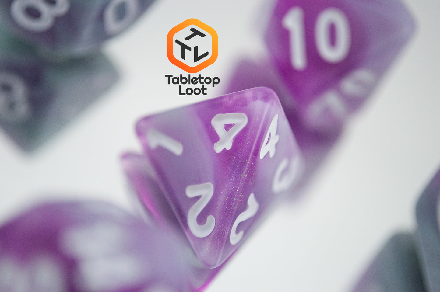 A close up of the D4 from the Stars Shine 7 piece dice set from Tabletop Loot with purple and grey shimmering swirls and white numbering.