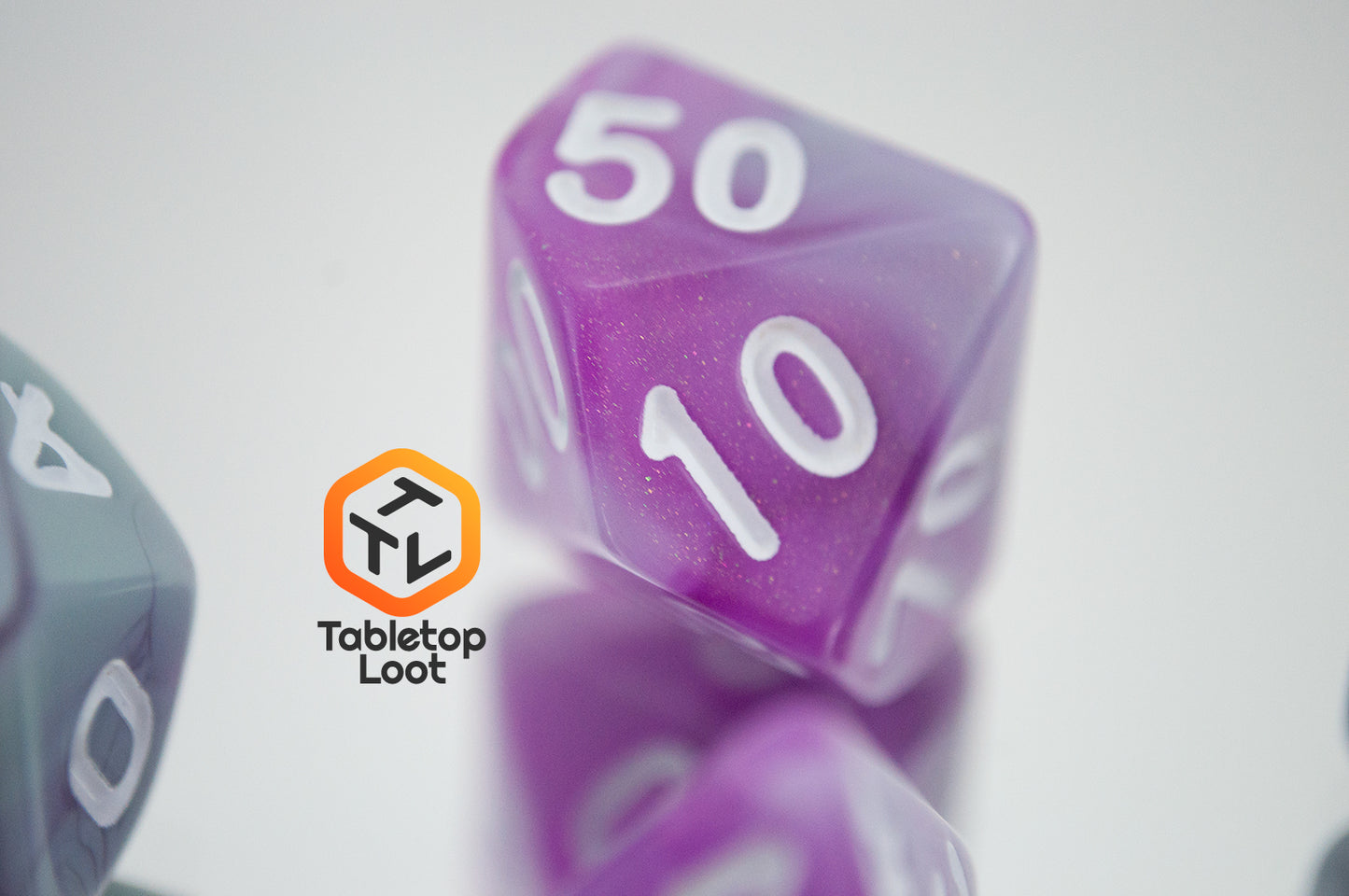 A close up of the percentile die from the Stars Shine 7 piece dice set from Tabletop Loot with purple and grey shimmering swirls and white numbering.
