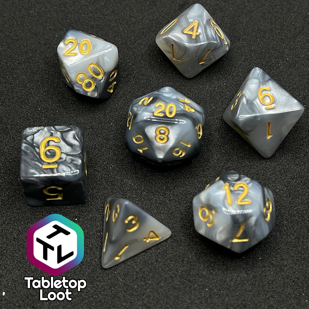 The Stone Giant 7 piece dice set with swirls of iridescent silver and white and gold numbering.