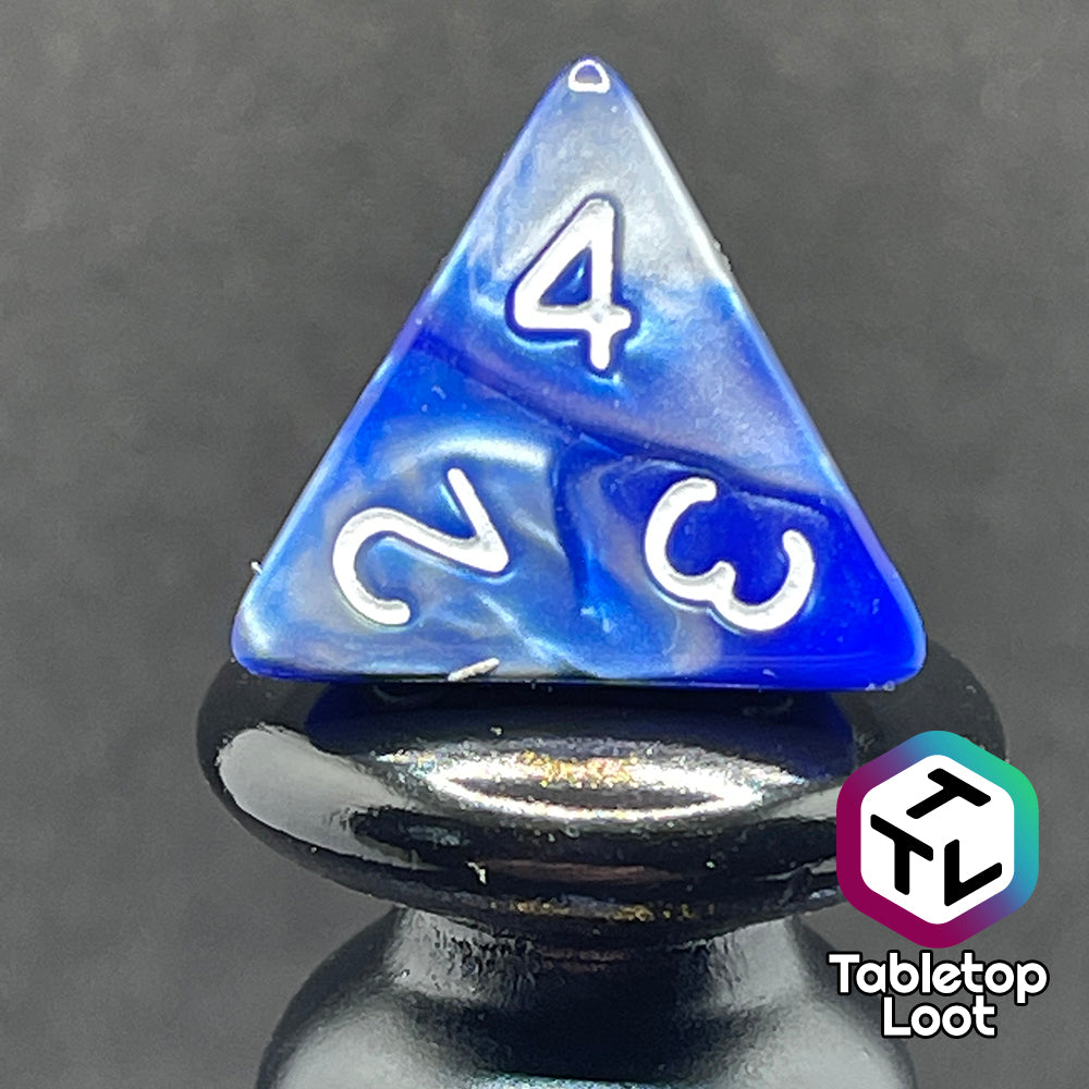 A close up of the D4 from the Storm Giant 7 piece dice set from Tabletop Loot with swirls of pearlescent blue and silver and white numbering.