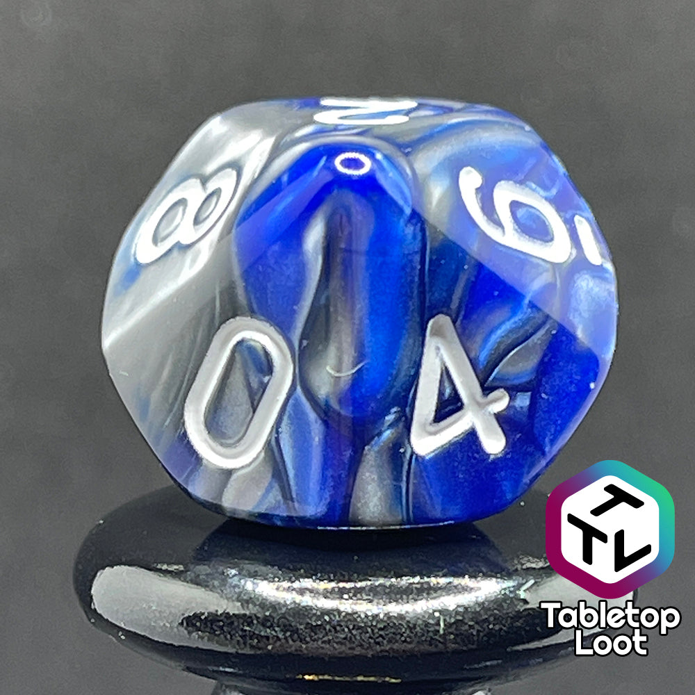 A close up of the D10 from the Storm Giant 7 piece dice set from Tabletop Loot with swirls of pearlescent blue and silver and white numbering.