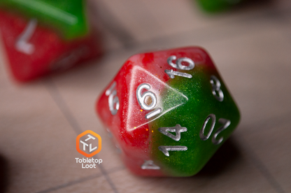 A close up of the D20 from the Strawberry Fields 7 piece dice set with sparkling layers of red and green and silver numbering.