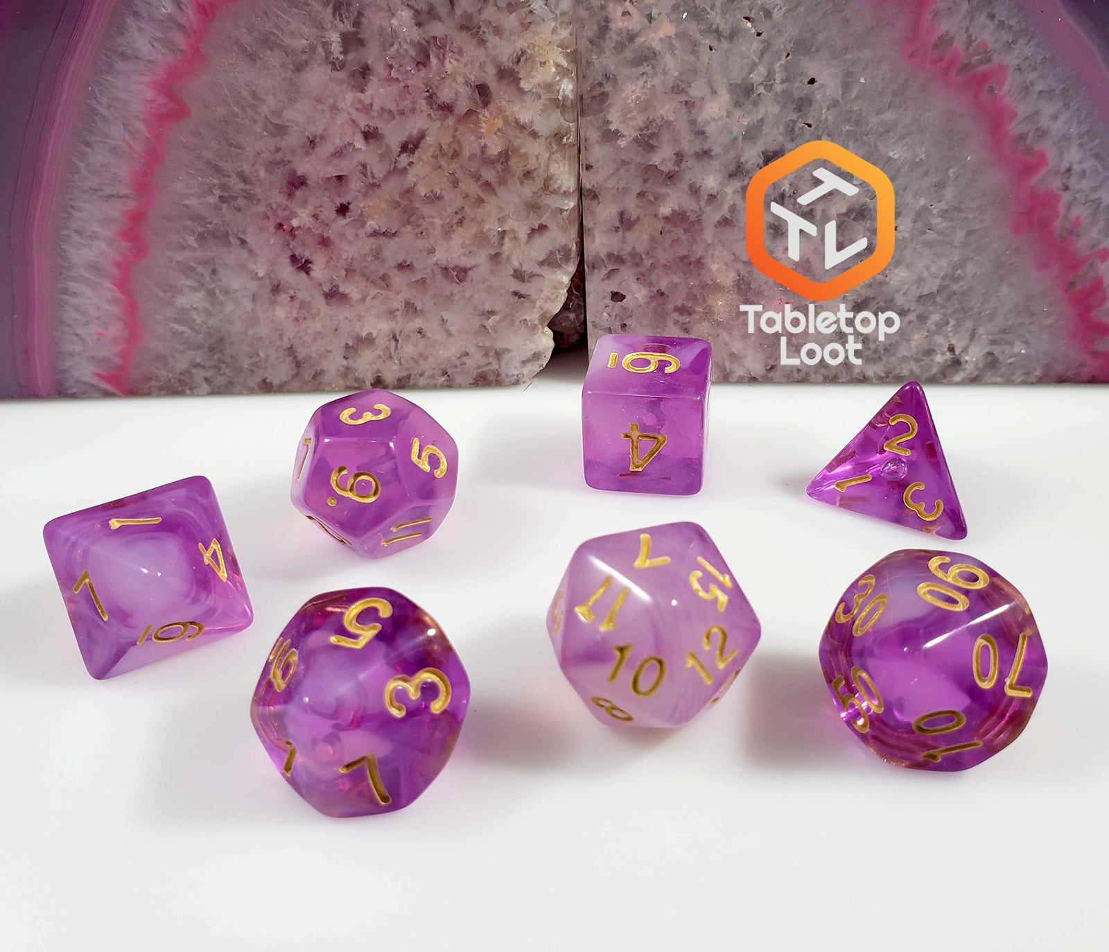 The Amethyst Geode 7 piece dice set from Tabletop Loot with swirls of purple and white resin and gold numbering.
