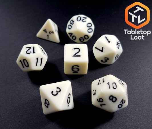 The Bleached Bone 7 piece dice set from Tabletop Loot with matte white resin and black numbering.
