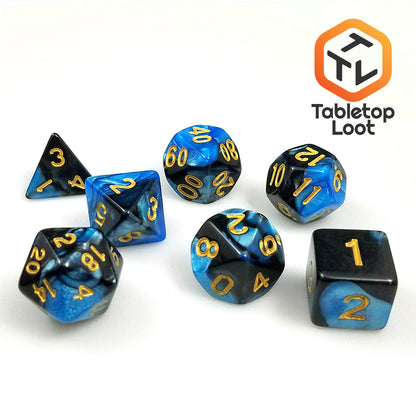 The Blue Drake 7 piece dice set from Tabletop Loot with blue and black pearlescent resin swirls and gold numbering.