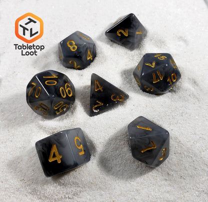 The Crystallized Smoke 7 piece dice set from Tabletop Loot with swirls of black and grey resin and gold numbers.