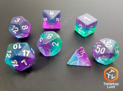 The Crystalline Fluorite 7 piece dice set from Tabletop Loot with layers of green, blue, and purple resin and silver numbering.
