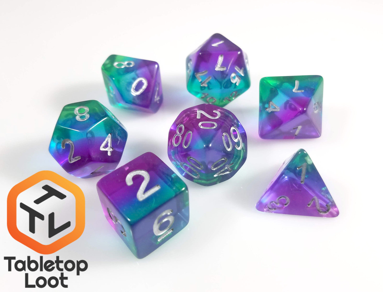 The Crystalline Fluorite 7 piece dice set from Tabletop Loot with layers of green, blue, and purple resin and silver numbering.