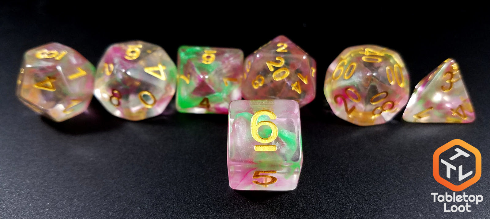 A close up of the D6 from the Fae Berry 7 piece dice set from Tabletop Loot with pink and green swirls through clear resin and gold numbering.