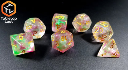 The Fae Berry 7 piece dice set from Tabletop Loot with pink and green swirls through clear resin and gold numbering.