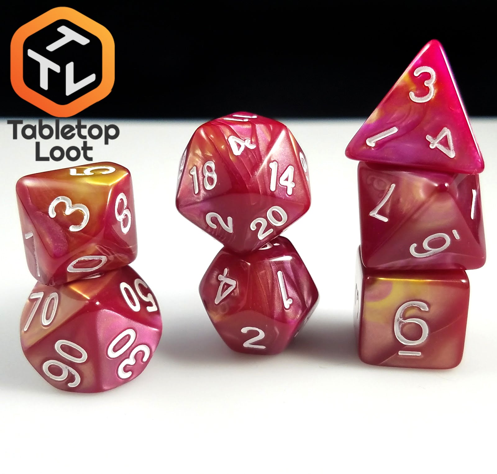 The Fire Opal 7 piece dice set from Tabletop Loot with swirls of pearlescent red and yellow and white numbering.'