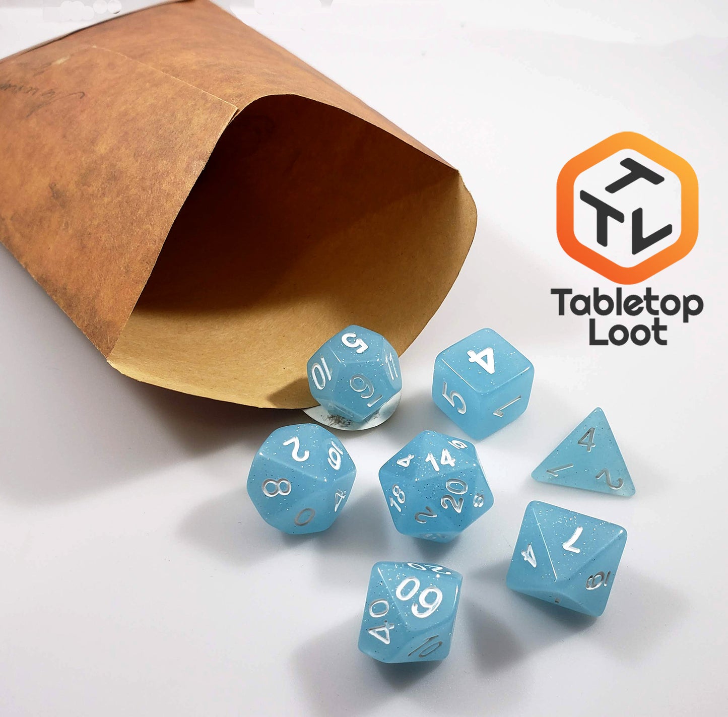 The Frosted Blueberry 7 piece dice set from Tabletop Loot with light blue sparkly resin and silver numbering.