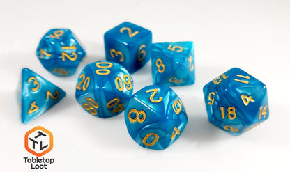 The Gilded Turquoise 7 piece dice set from Tabletop Loot with swirls of turquoise resin and gold numbering.