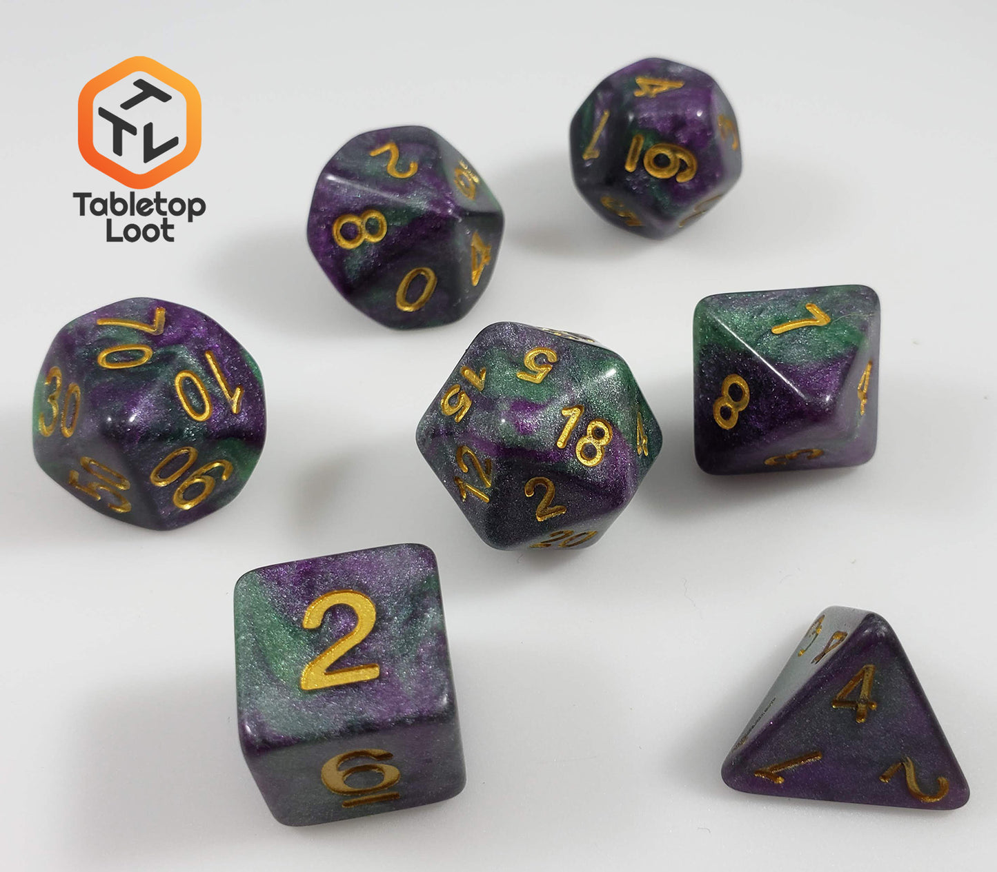 The King Cake 7 piece dice set from Tabletop Loot with swirls of green and purple shimmery resin and gold numbering.