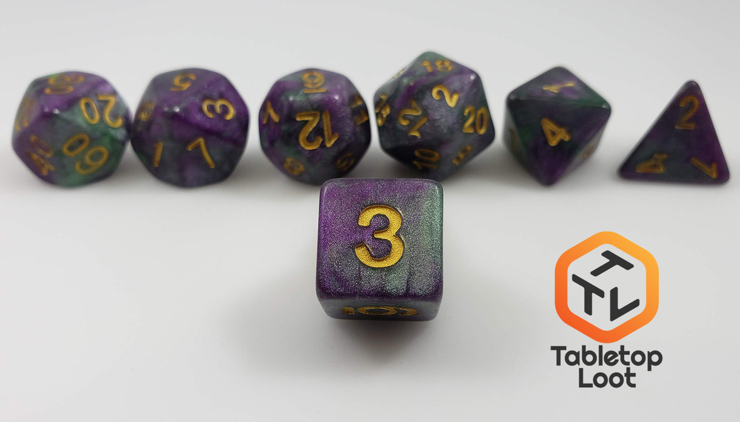 A close up of the D6 from the King Cake 7 piece dice set from Tabletop Loot with swirls of green and purple shimmery resin and gold numbering.