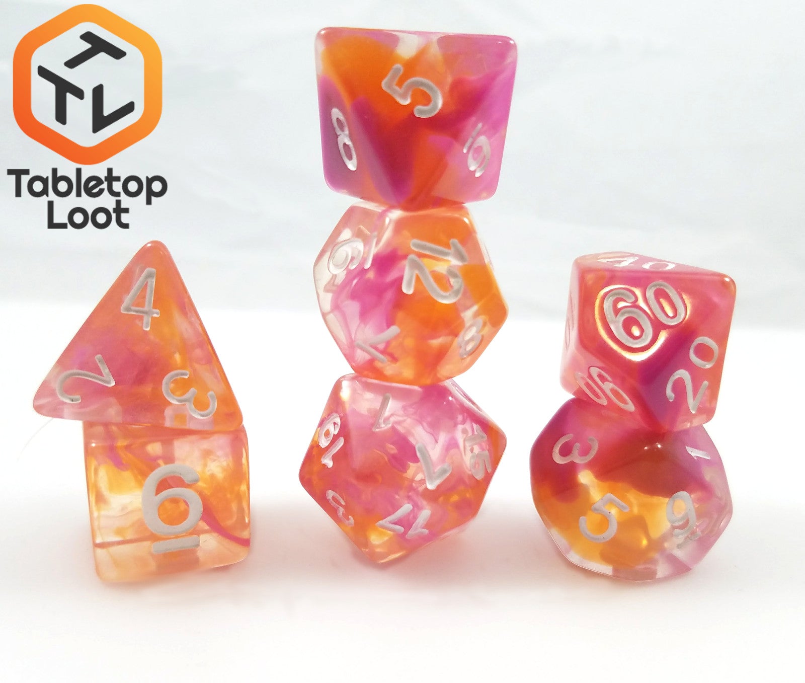 The Pink Lemonade 7 piece dice set from Tabletop Loot with swirls of pink, orange, and yellow in clear resin with white numbering.