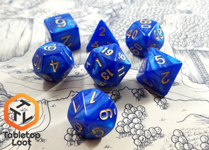 The Royal Sapphire 7 piece dice set from Tabletop Loot with swirls of blue resin and gold numbering.