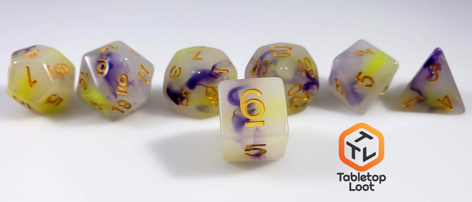 A close up of the D6 from the Fields of Wildflowers 7 piece dice set from Tabletop Loot with swirls of purple and yellow in a milky resin and gold numbering.