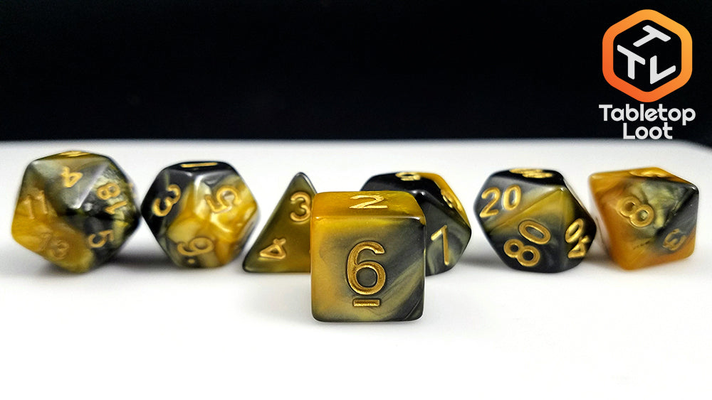 The Hornet Swarm 7 piece dice set from Tabletop Loot with gold and black swirled resin and gold numbering.