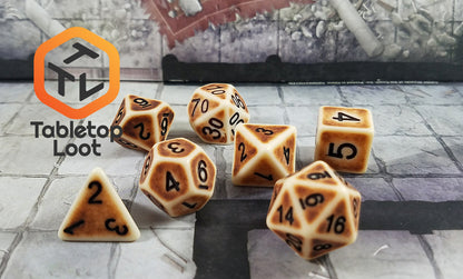 The Dragon Bone 7 piece dice set from Tabletop Loot with a matte finish, brown aged sides, and black numbering.