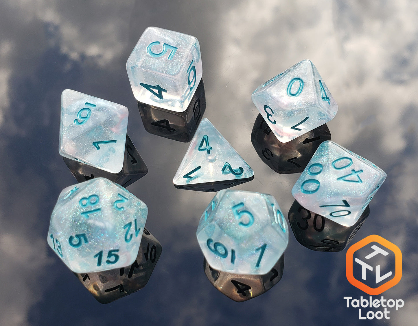 The Wall of Ice 7 piece dice set from Tabletop Loot with tons of glitter in a translucent resin with teal numbering.
