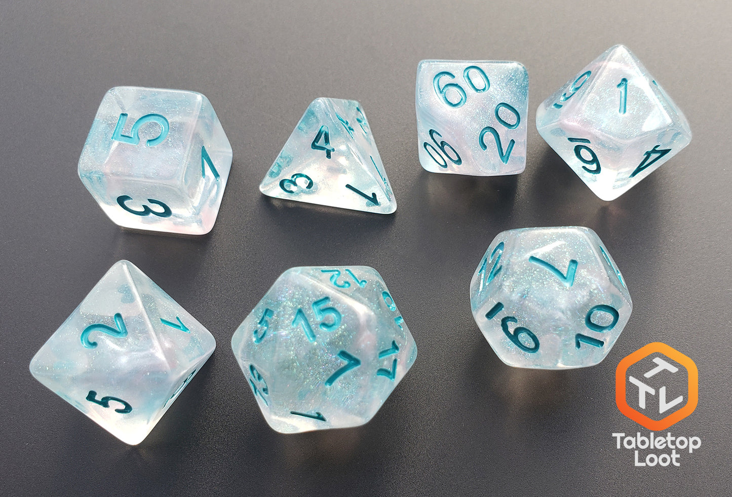 The Wall of Ice 7 piece dice set from Tabletop Loot with tons of glitter in a translucent resin with teal numbering.