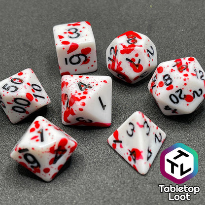 A close up of the Tavern Brawl 7 piece dice set from Tabletop Loot; white dice with fake blood splatter and black numbering.