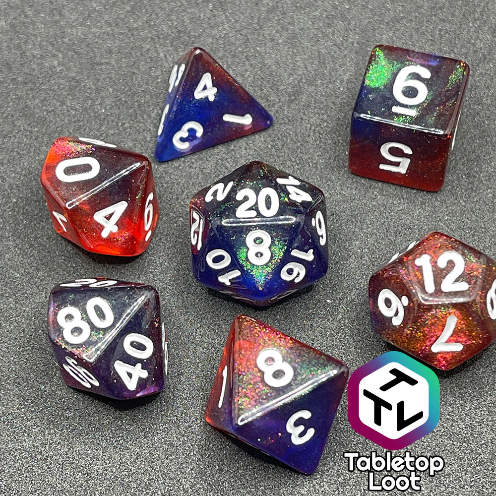 The Transmutation 7 piece dice set from Tabletop Loot with swirls of blue and red appearing purple in some spots, filled with iridescent glitter adding little rainbows in places, and inked in white.