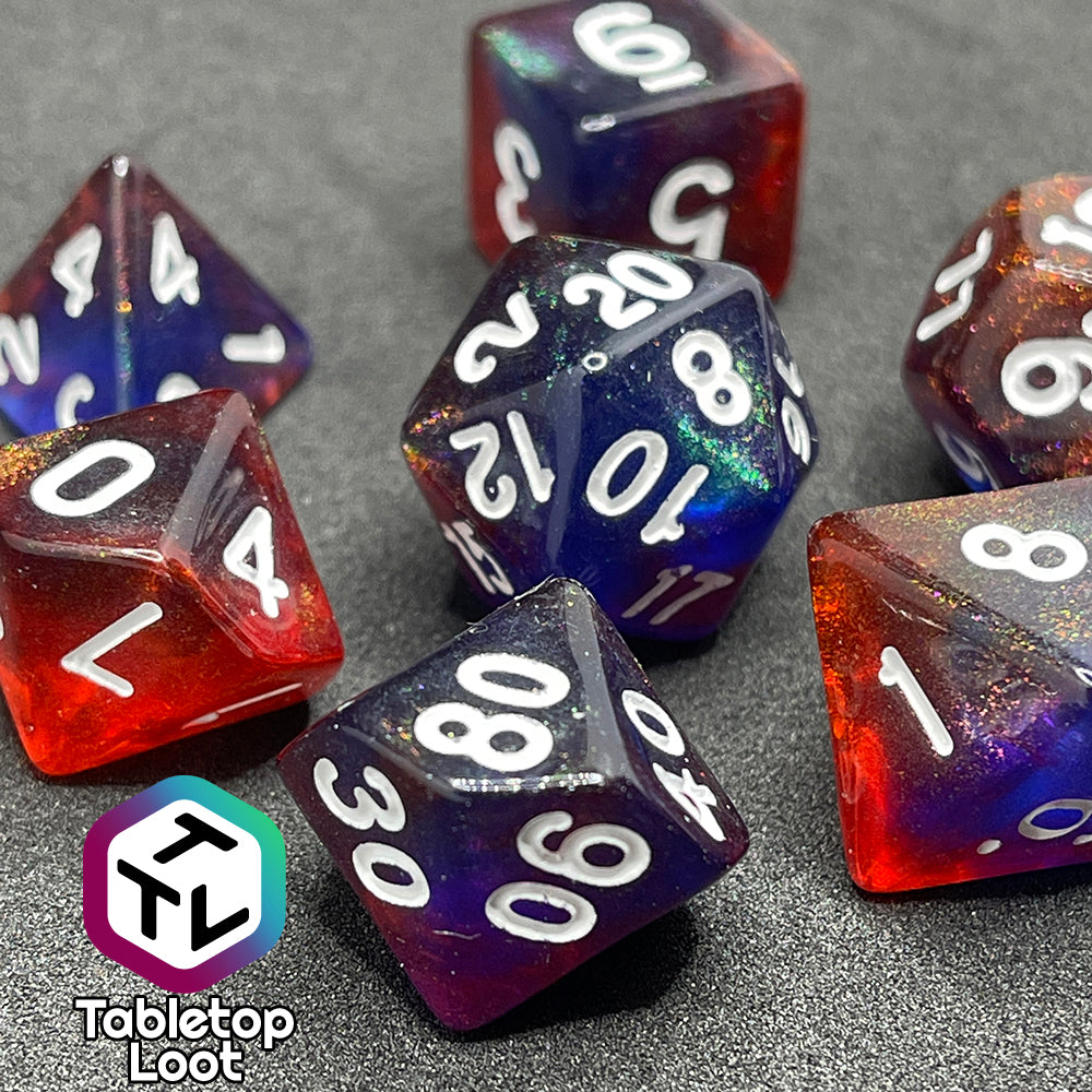 A close up of the Transmutation 7 piece dice set from Tabletop Loot with swirls of blue and red appearing purple in some spots, filled with iridescent glitter adding little rainbows in places, and inked in white.