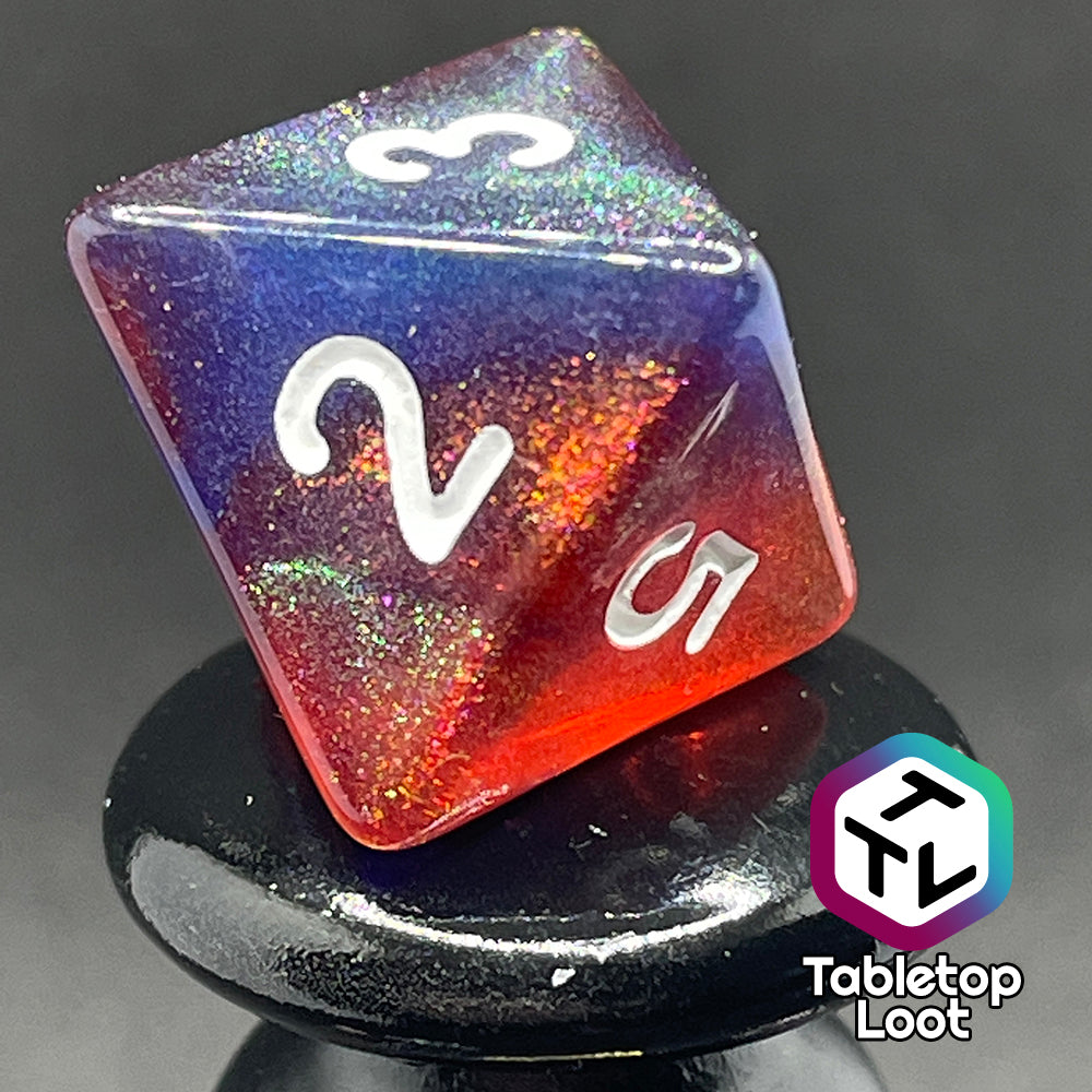 A close up of the D8 from the Transmutation 7 piece dice set from Tabletop Loot with swirls of blue and red appearing purple in some spots, filled with iridescent glitter adding little rainbows in places, and inked in white.