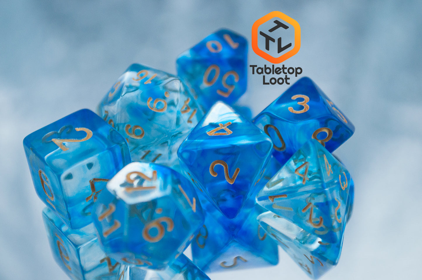 The Under the Sea 7 piece dice set from Tabletop Loot with swirls of blue and gold numbering.