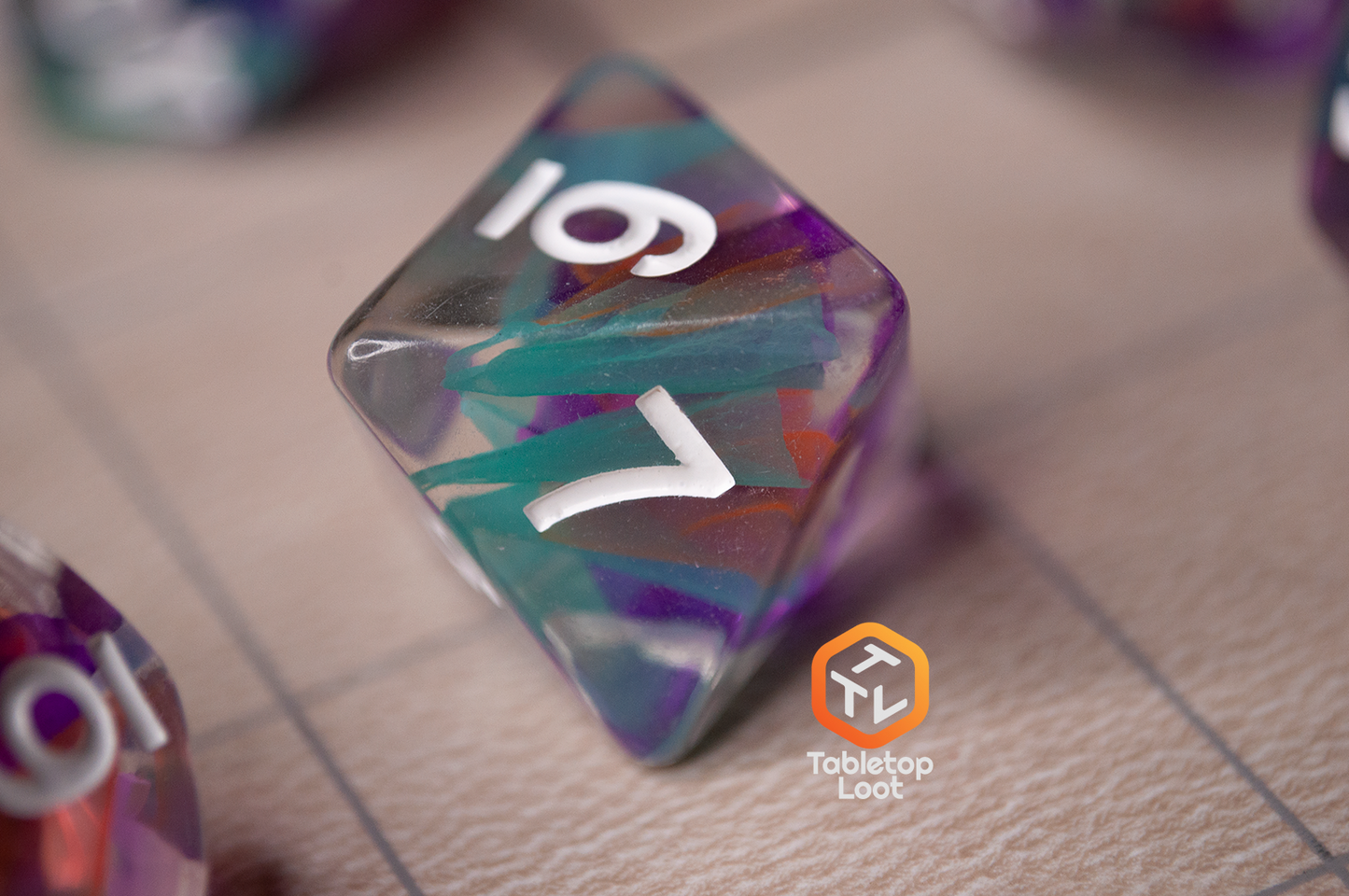 A close up of the Raise the Banners D8 made with strips of color swirled through the middle of clear resin.