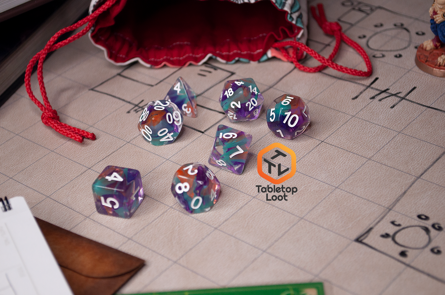 The Raise the Banners dice set, clear with swirled orange, blue, and purple resin, on a gaming table.