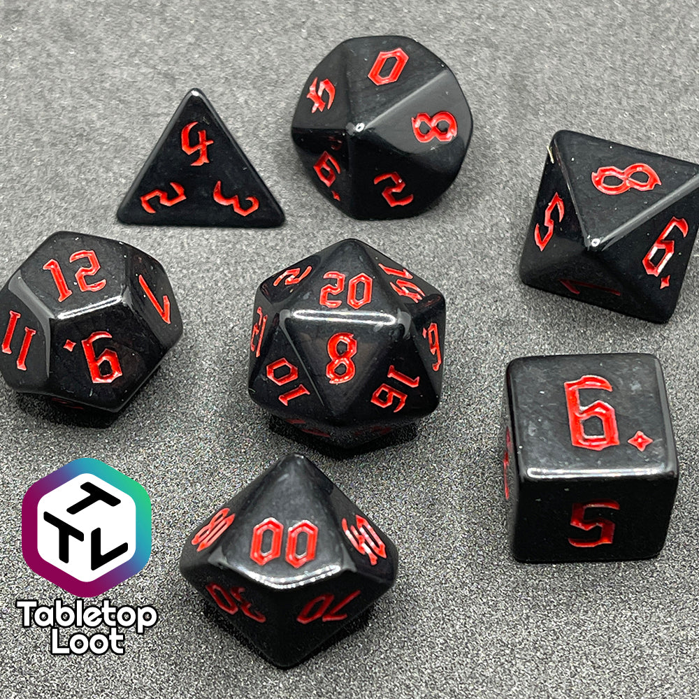 The Vampiric Touch 7 piece dice set from Tabletop Loot; reflective black with red numbering in a bold gothic font.