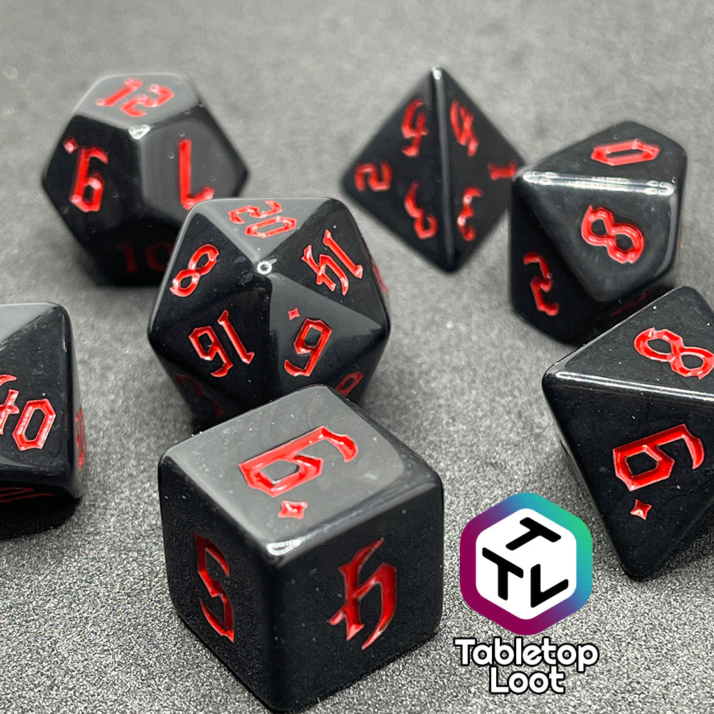 A close up of the Vampiric Touch 7 piece dice set from Tabletop Loot; reflective black with red numbering in a bold gothic font.