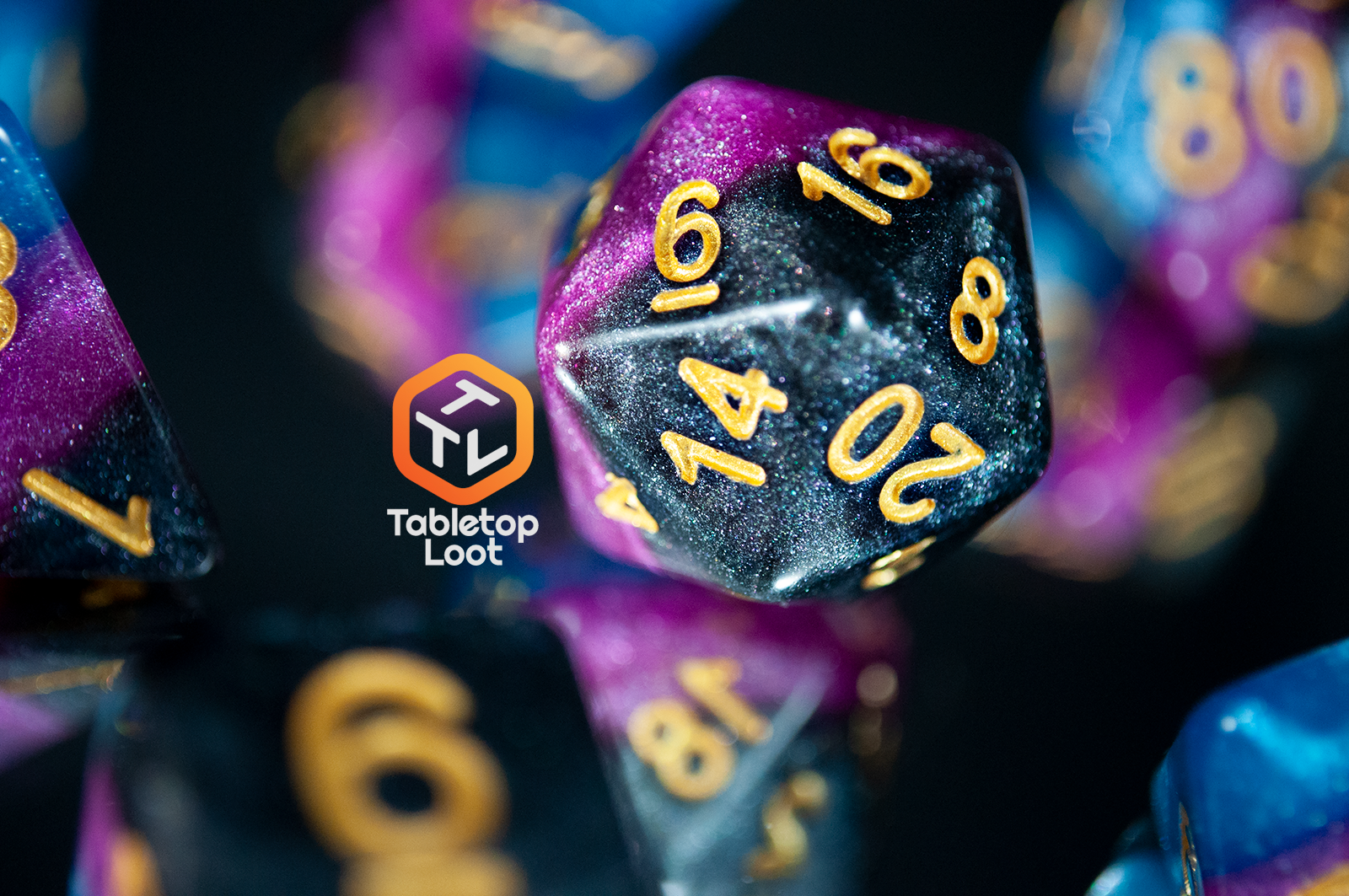 A close up of the Pulse Wave D20 made with blue, purple, and black stripes of color and lots of glitter, inked in gold.